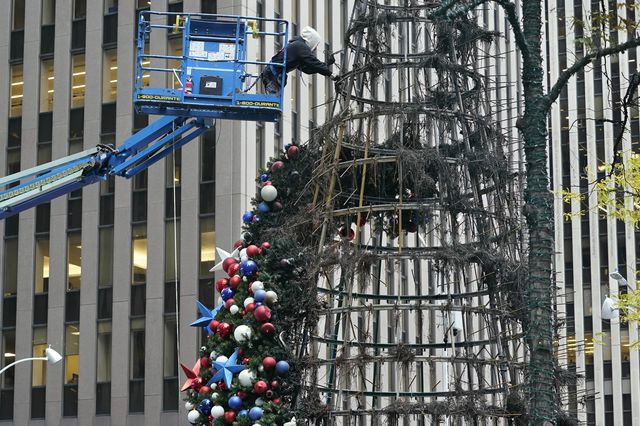 A worker on a cherry picker removes ornaments from the wire frame of the burned Christmas tree display